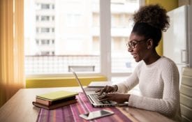 Black Woman sitting at home using laptop and studying
