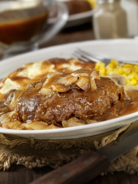 Salisbury Steak Topped with Sauteed Mushrooms and Onions, Mashed Potatoes and Corn on the side and topped with Gravy.