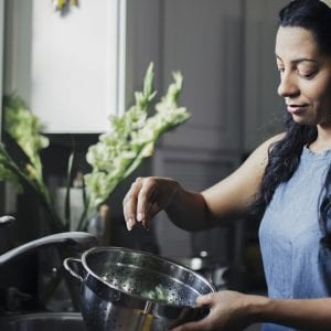Woman washing food in colander