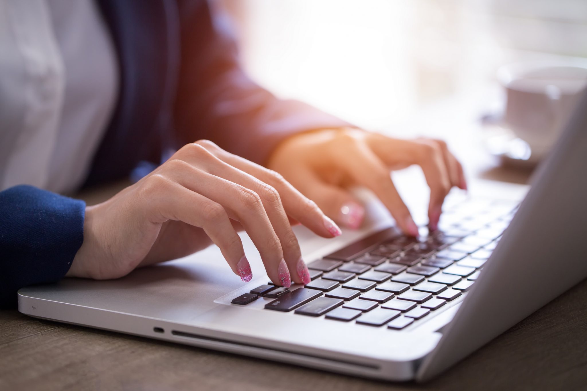Close-up of hands typing on laptop keyboard in the office.