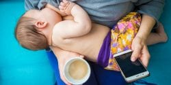 A woman breastfeeding and drinking a cup of coffee