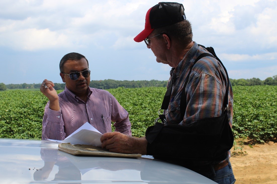 Rishi Prasad visiting with grower in the field