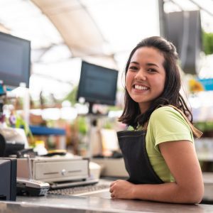 A young woman standing in front of a cash register.