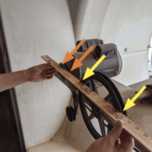 Figure 6. Hold the yardstick across the face of both the motor and fan pulleys. We have removed the fan belt during this check. You want to have four points of contact (shown by the orange arrows for the motor pulley and yellow arrows for the fan pulley). Make sure not to lap over the raised area near the shaft; this will give a false reading.