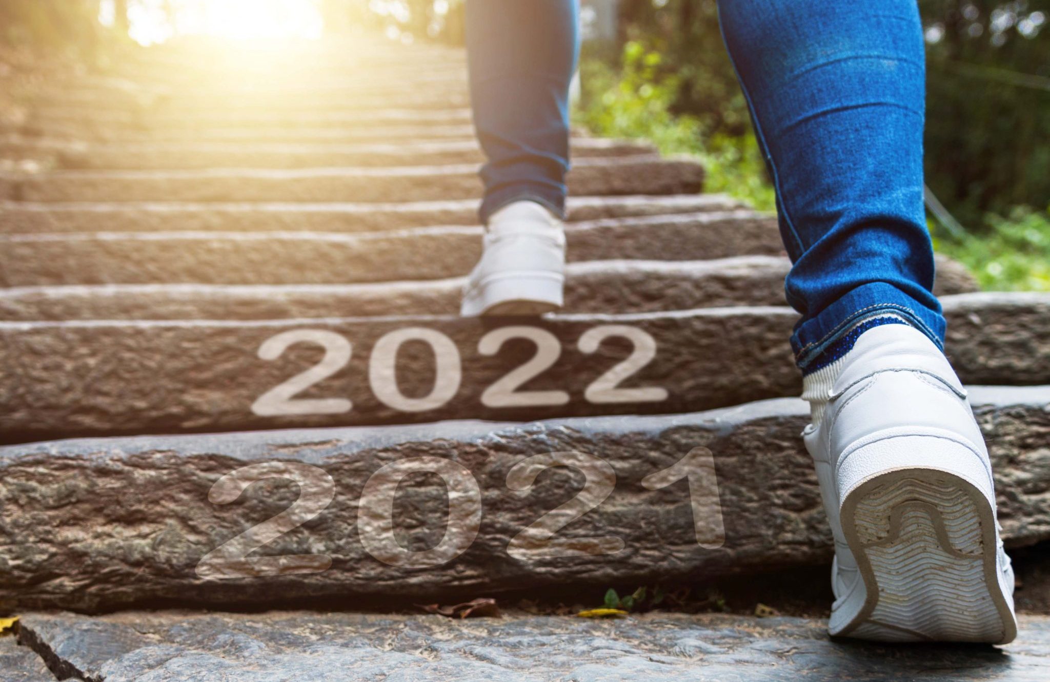 Woman legs walking up stone stairs with number 2022 and 2021