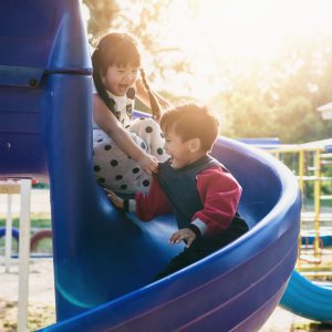 Two children playing on a slide