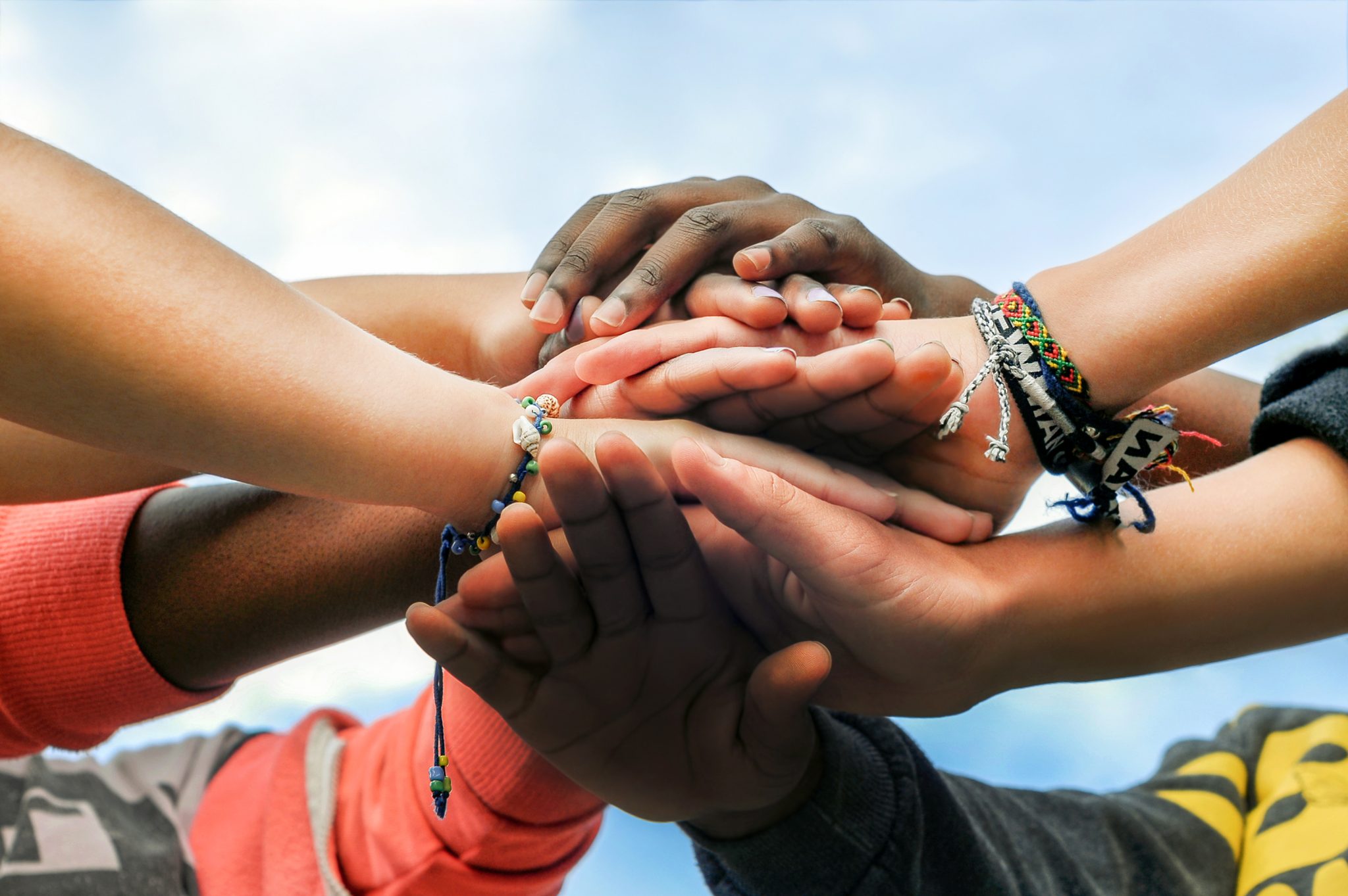 A group of stacked hands from a diverse group of young people.