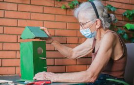 elderly woman with face mask making a birdhouse