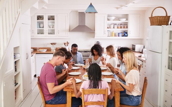 Two families praying at the dinner table