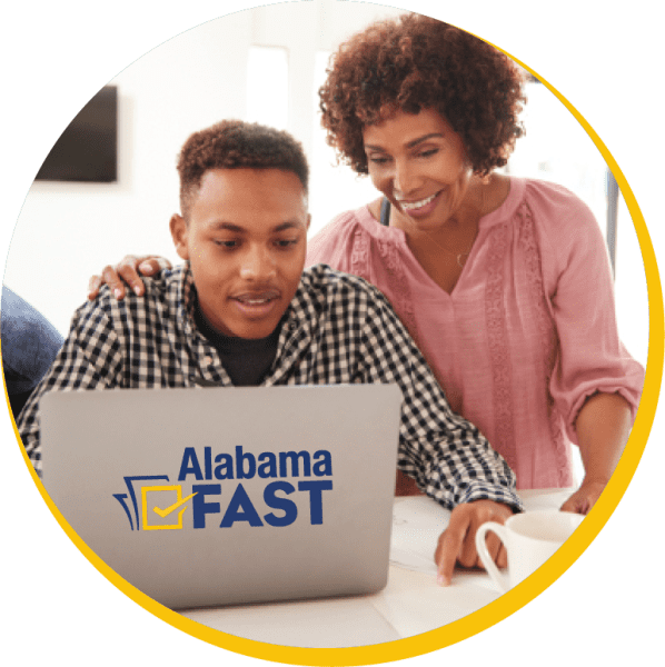 A black mom and son standing over a computer.