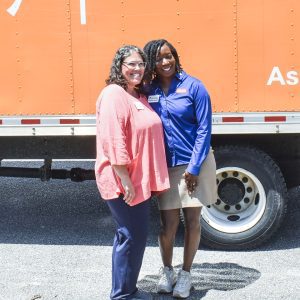 two women posing for photo in front of orange truck