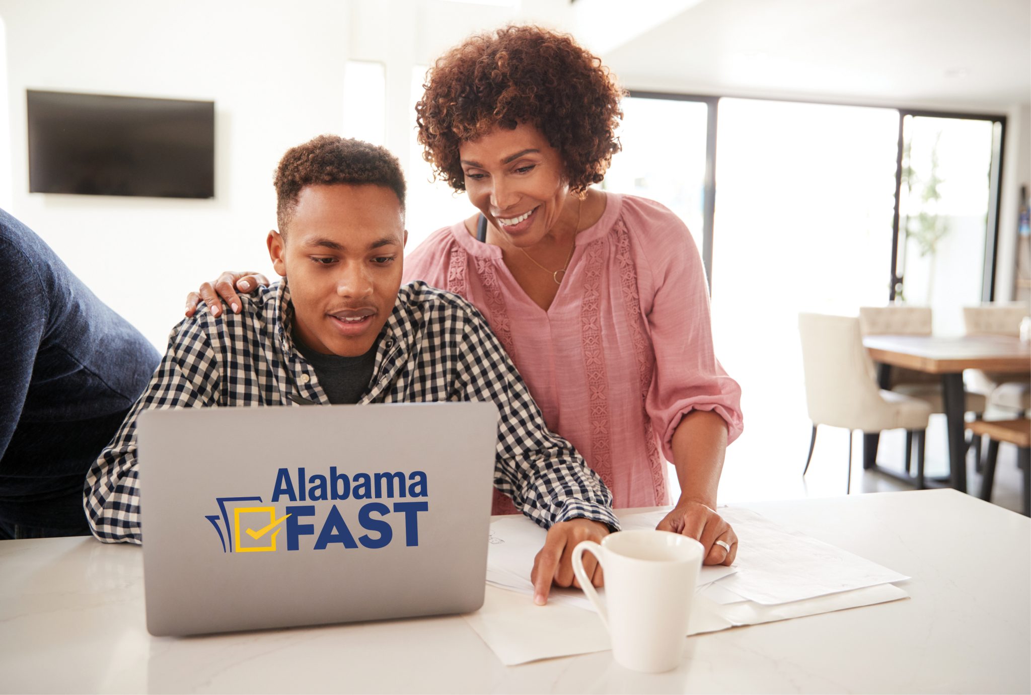A black mother and teenage son sitting at a computer together.