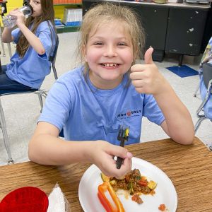 young girl, blue shirt give thumbs up