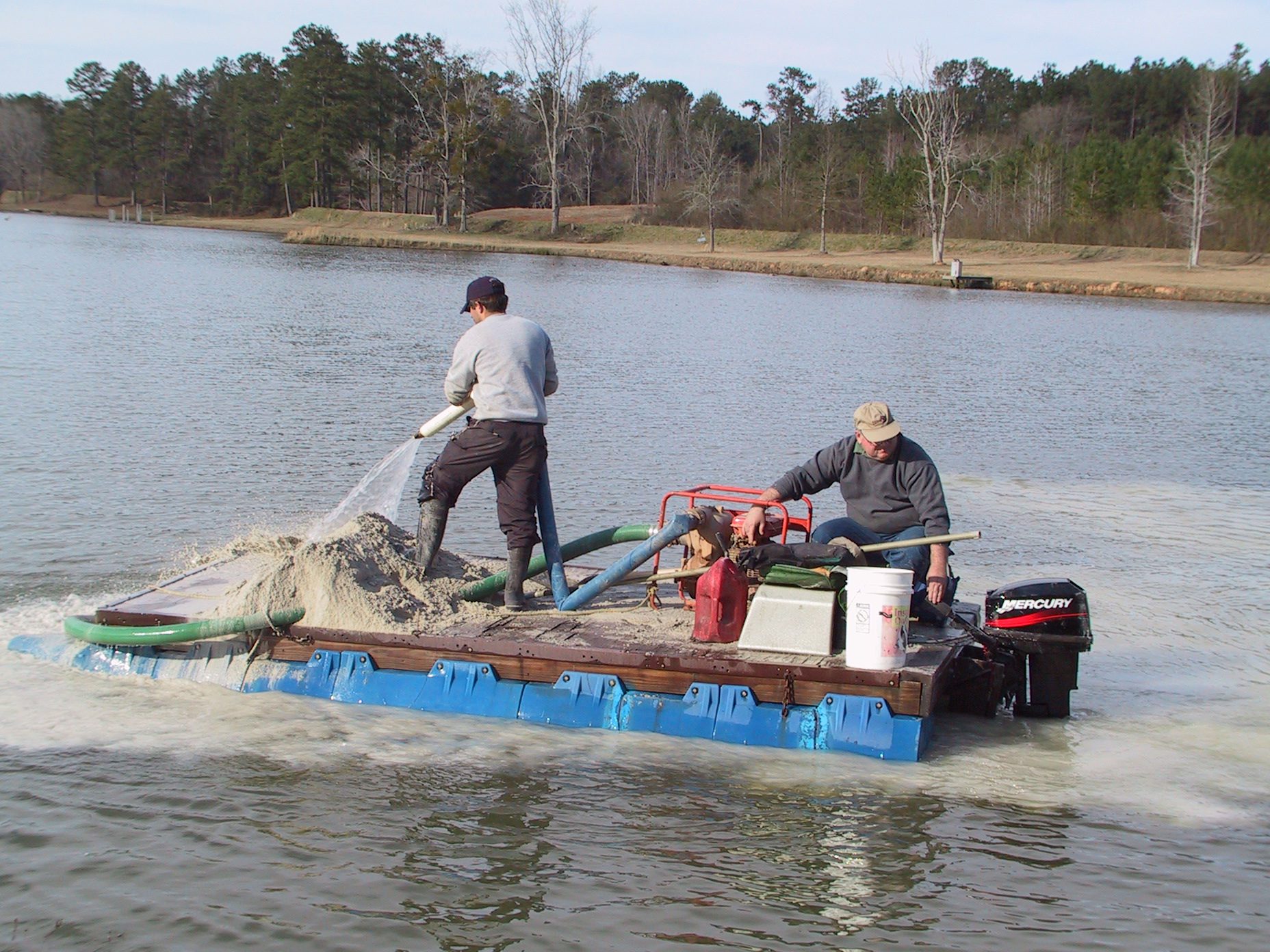 Lime application using a pontoon barge and water pump to evenly distribute the lime.