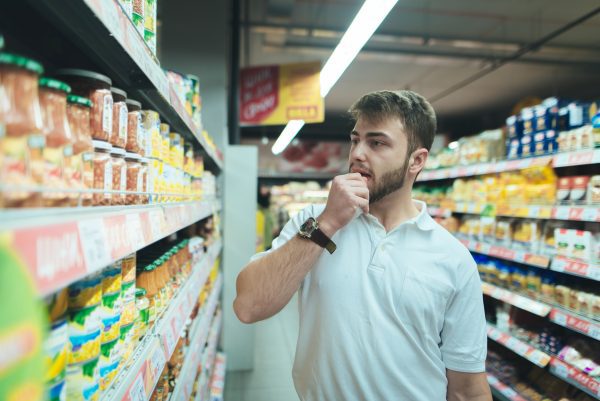 A man looking at canned items in a grocery store.