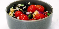 Mediterranean Salad, red cherry tomatoes, black olives in grey bowl