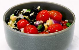 Mediterranean Salad, red cherry tomatoes, black olives in grey bowl