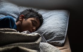 A Hispanic boy asleep in bed