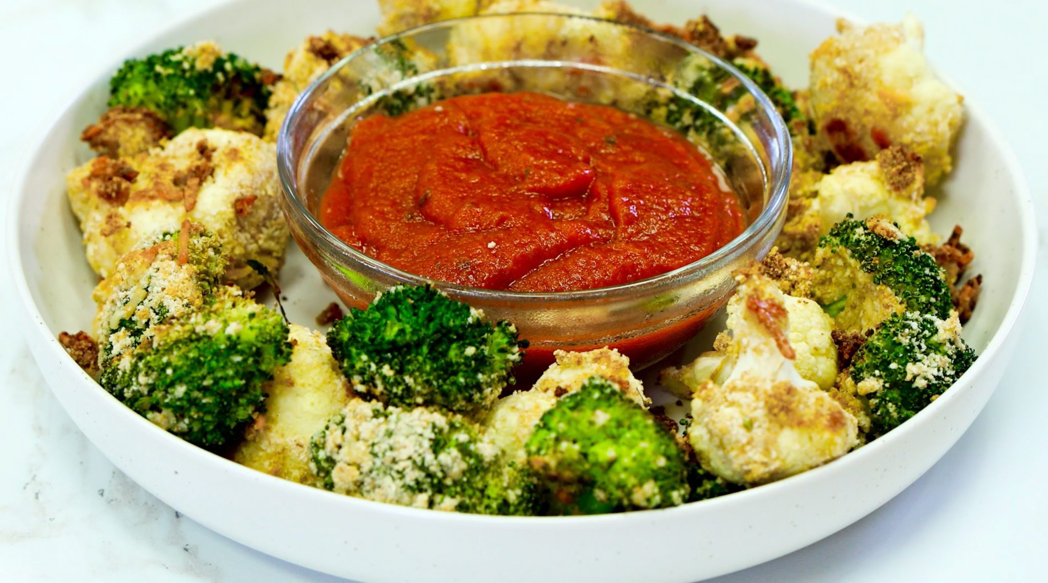Tree Dunkers, broccoli and cauliflower around red sauce in clear bowl