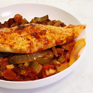 cooked chicken on a bed of vegetables in a tomato sauce