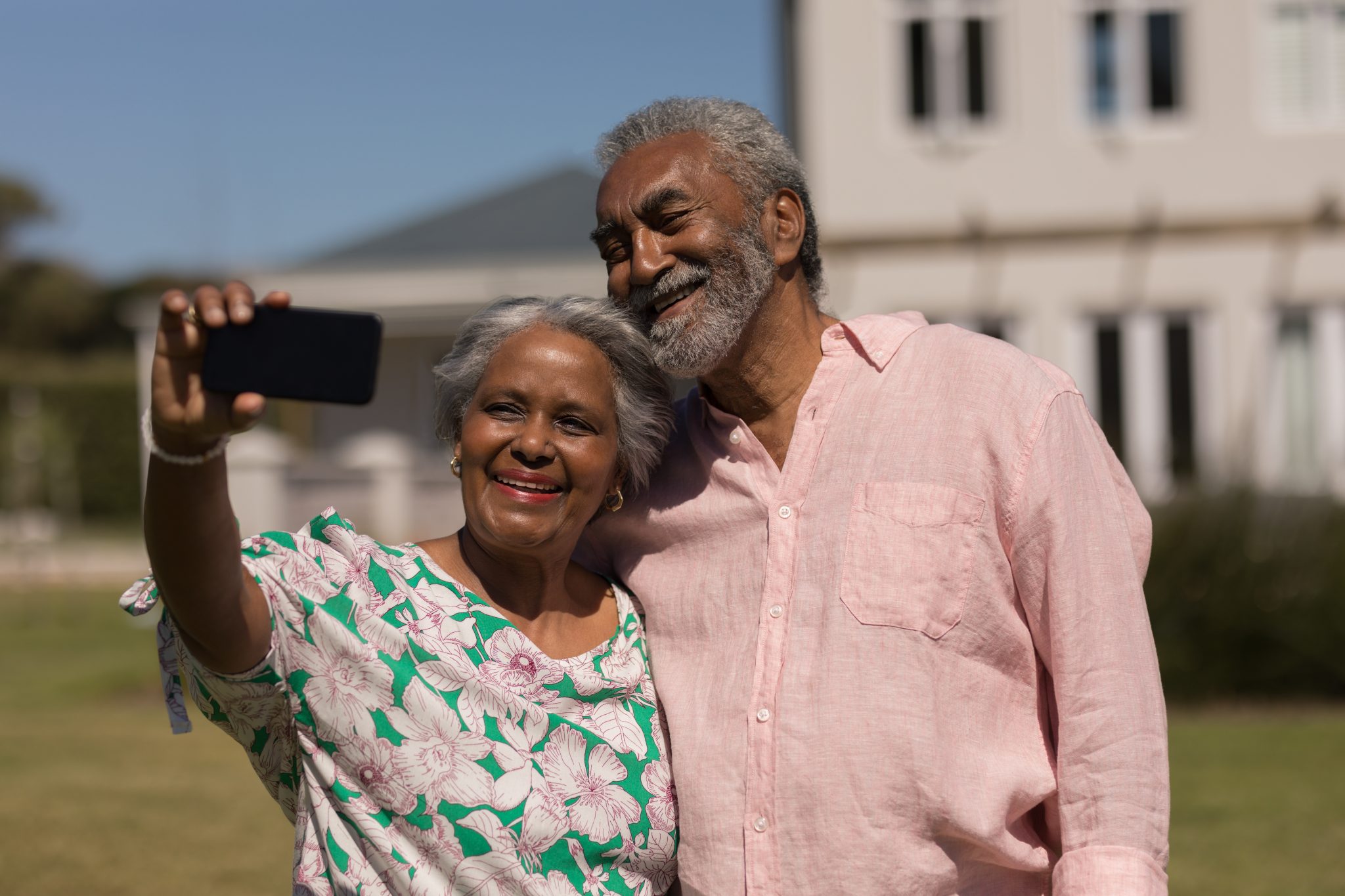 Front view of an active senior African American couple taking a selfie with mobile phone in the backyard on a sunny day