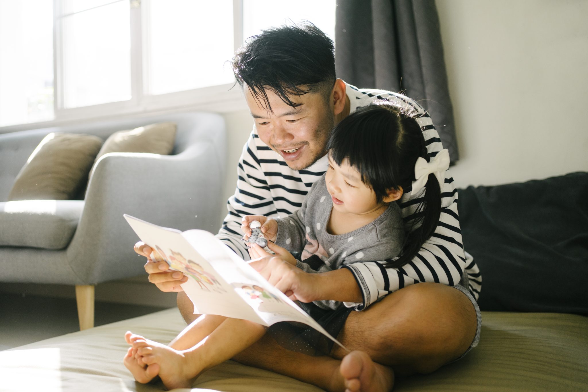 An asian father reading with his daughter