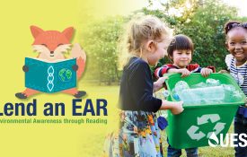 Three elementary-school children smile as the carry a recycling bin. The words, "Lend and EAR: Environmental Awareness through Reading" appear to the left of the children.