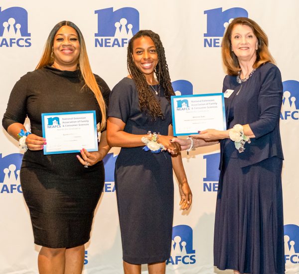 Three women holding two awards