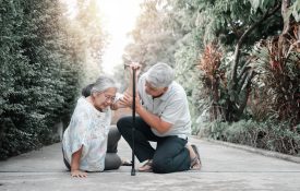 Asian senior woman falling down on lying floor at home after Stumbled at the doorstep and Crying in pain and her husband came to help support. Concept of old elderly insurance and health care
