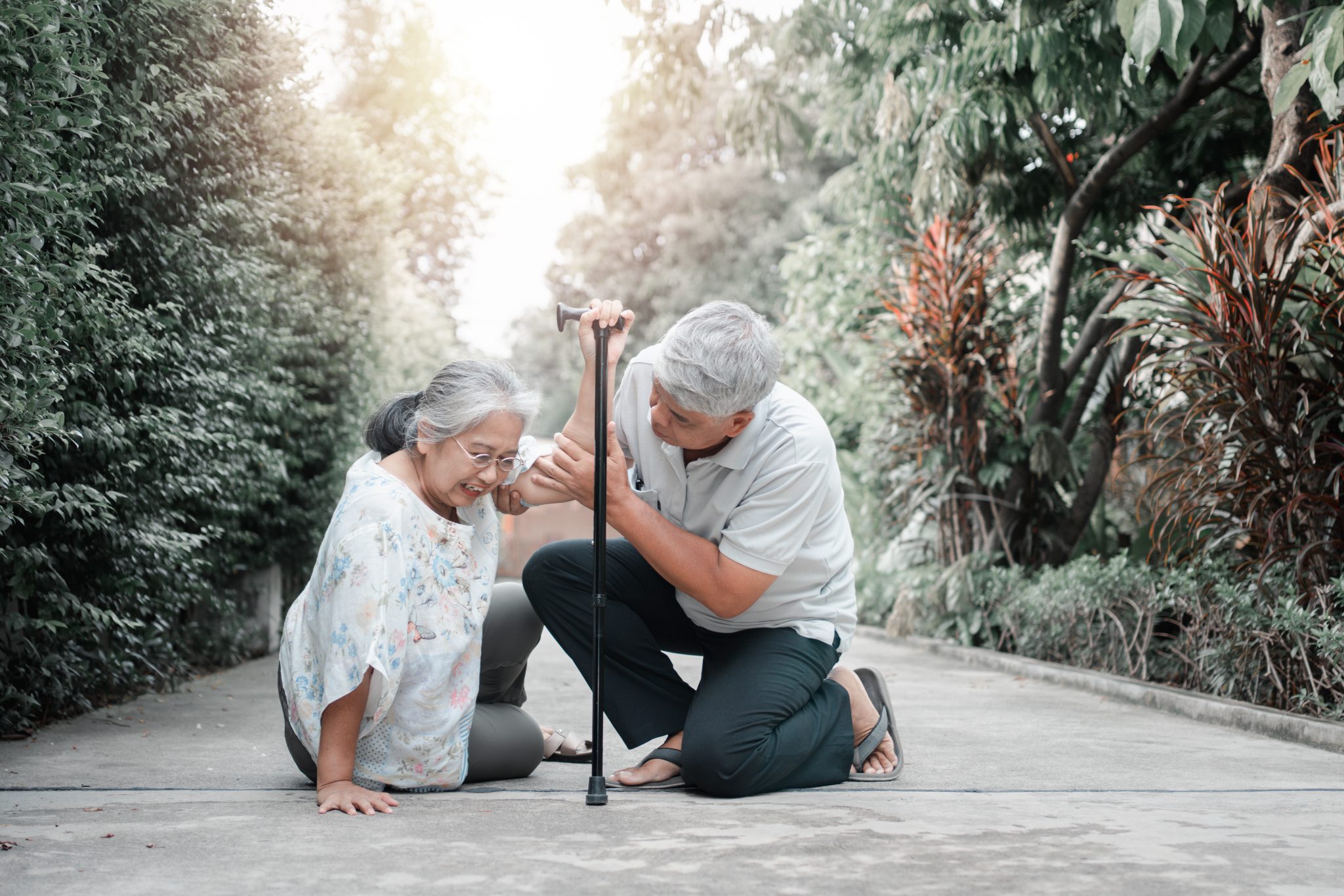 Asian senior woman falling down on lying floor at home after Stumbled at the doorstep and Crying in pain and her husband came to help support. Concept of old elderly insurance and health care