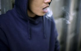 Young black man in a hoodie with smoke coming out of his mouth