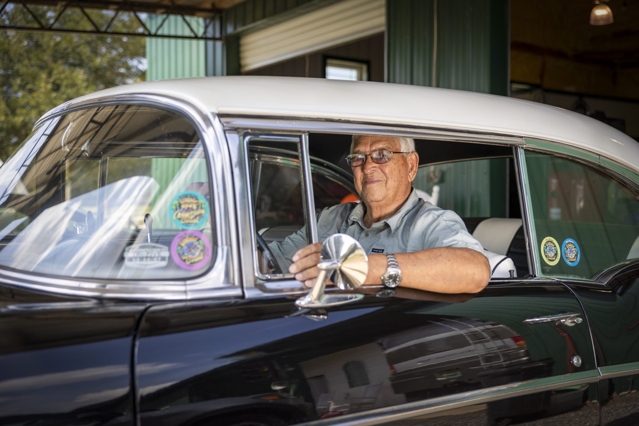 Eddie Tullis sitting in the driver's seat of a black 1957 Chevrolet