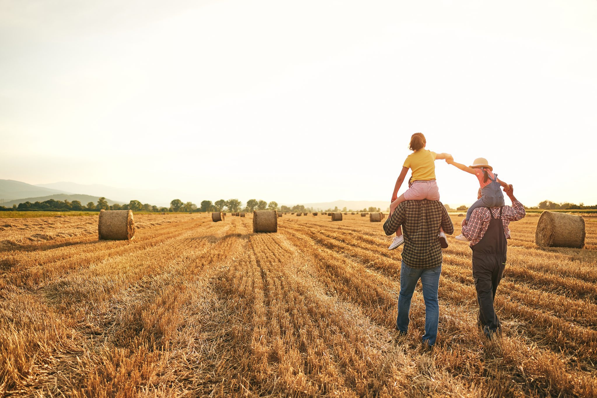 A family walking through a hay field.