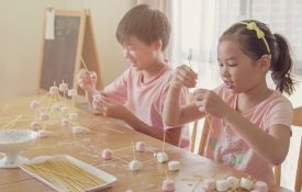 Two young Asian children building marshmallow towers