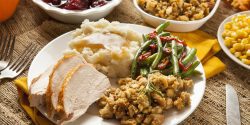 A plate of Thanksgiving food, including turkey, mashed potatoes, green beans, and stuffing.