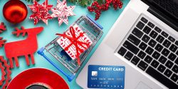 Shopping online with credit card for christmas holiday. Laptop with gifts on table on cyan blue background