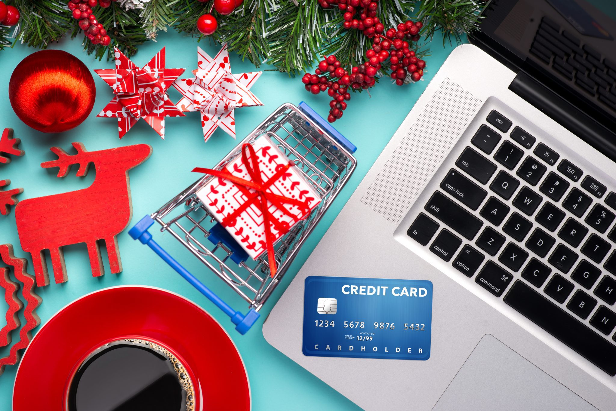 Shopping online with credit card for christmas holiday. Laptop with gifts on table on cyan blue background