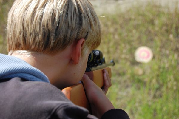 Young boy practicing shooting at an outside target