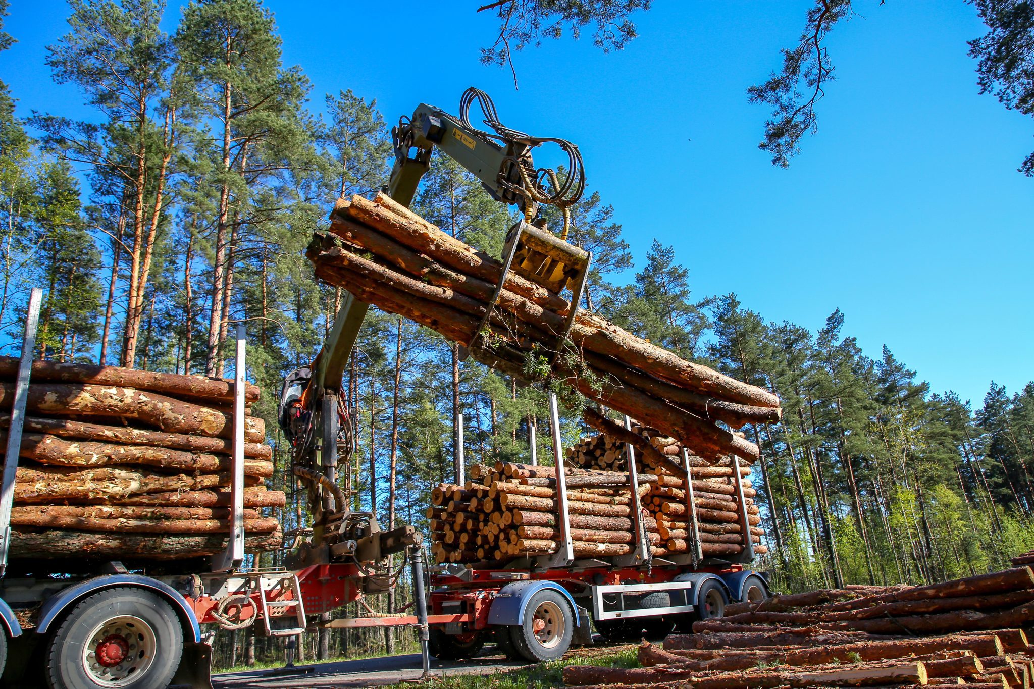 A truck loading logs onto a trailer for transportation