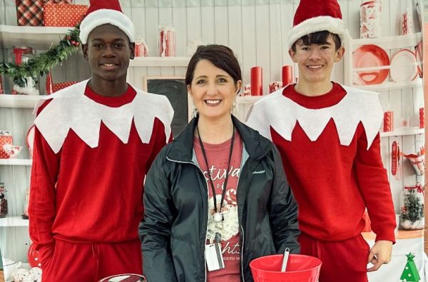 woman standing between two men in red holiday clothes