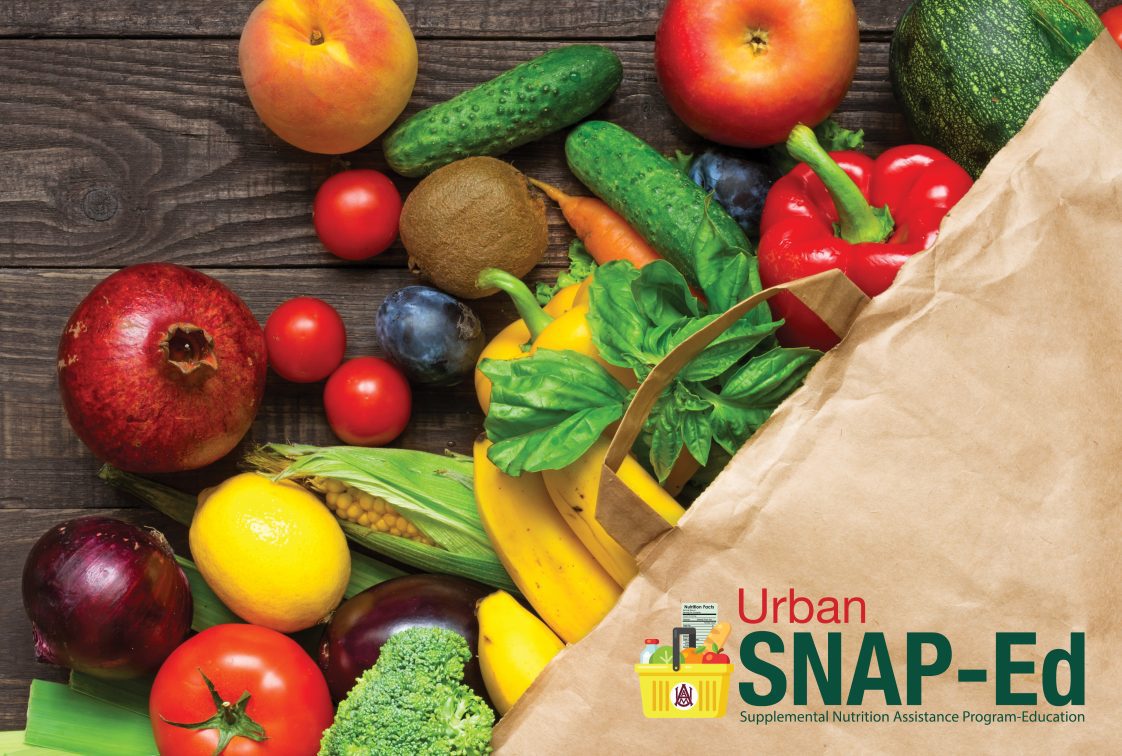 Paper grocery bag on its side with fresh fruits and vegetables falling out.
