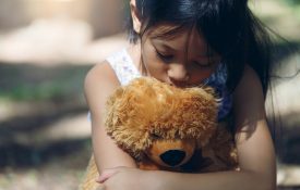 girl hugging teddy bear, using teddybear to recover well-being after a storm