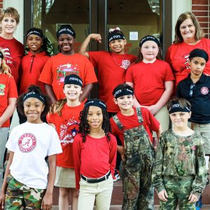 Several students in red pose for photo with teachers