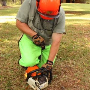 Figure 13. An alternative method for larger saws is to place your right knee on the chainsaw housing and follow the instructions for a ground start.