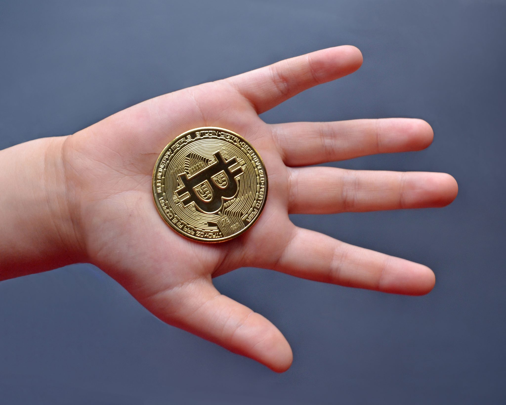 a child's hand holding bitcoin cryptocurrency