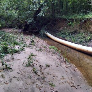 Exposed sewer line due to widening waterbody bank erosion