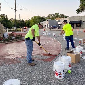 two men in green shirts paint a roundabout