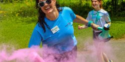 woman in blue shirt sprays pink dust during color run