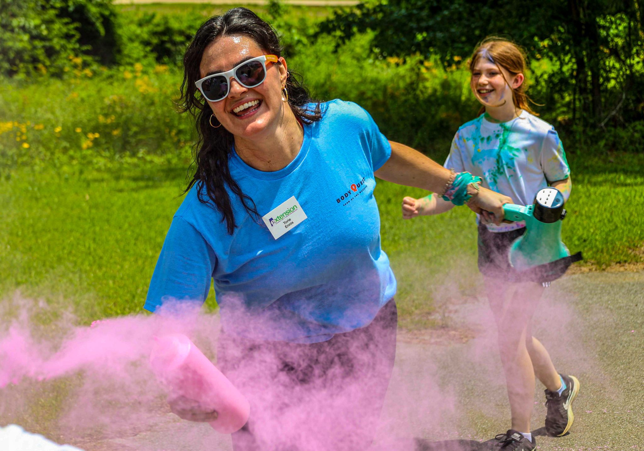 woman in blue shirt sprays pink dust during color run
