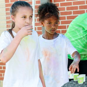 two girls drink water after color run
